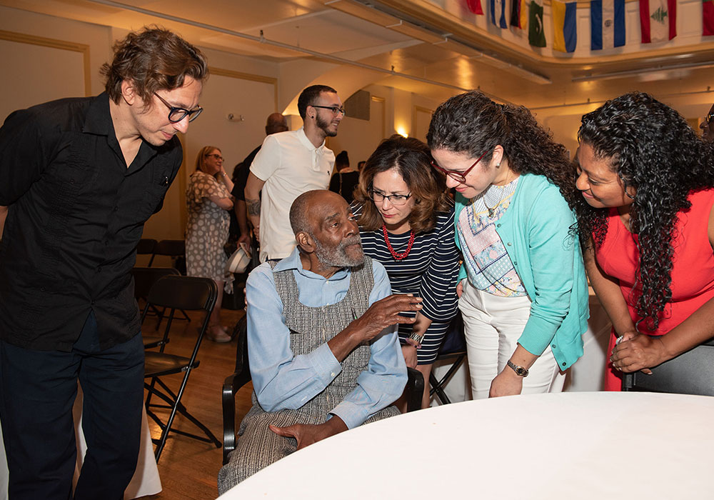 Mel King (seated) speaking with a group of individuals.