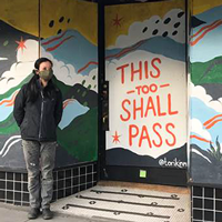 Woman shows her COVID recovery mural in front of a store in Seattle.